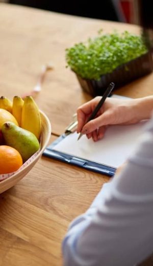 nutritionist-dietitian-woman-writing-diet-plan-with-healthy-vegetables-fruits-healthcare-diet-concept-female-nutritionist-with-fruits-working-her-desk-workplace_120485-9437 (1)